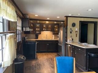 kitchen with dark wood-style flooring, a peninsula, dark brown cabinetry, glass insert cabinets, and appliances with stainless steel finishes