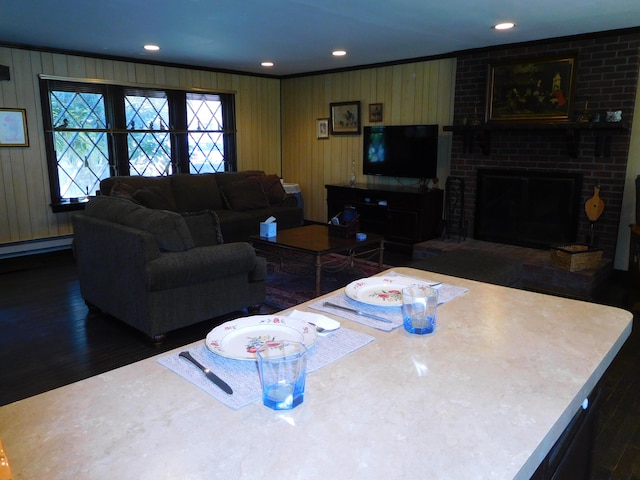 living area with a brick fireplace, wood finished floors, a baseboard radiator, ornamental molding, and recessed lighting