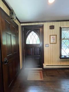 doorway to outside with wood finished floors, a wealth of natural light, and a baseboard radiator