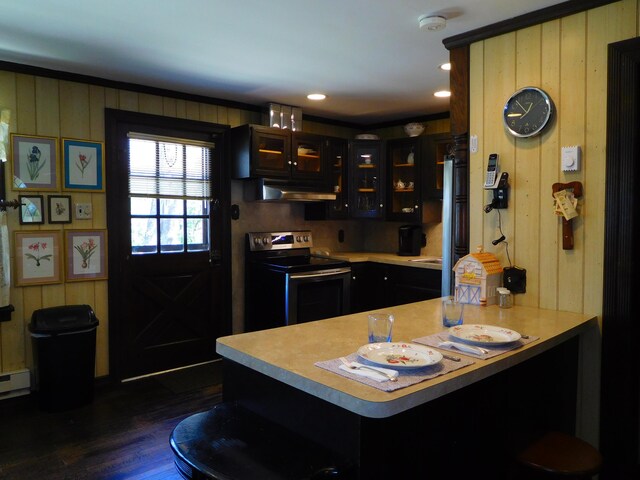 kitchen with stainless steel electric range oven, light countertops, a peninsula, dark wood-style floors, and under cabinet range hood