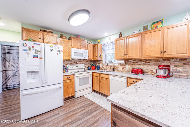 kitchen featuring light brown cabinets, decorative backsplash, light wood-style flooring, white appliances, and a sink