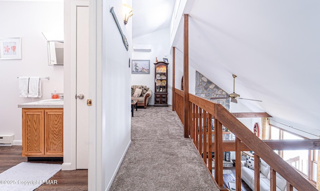 corridor featuring carpet, baseboards, vaulted ceiling with beams, a sink, and an upstairs landing