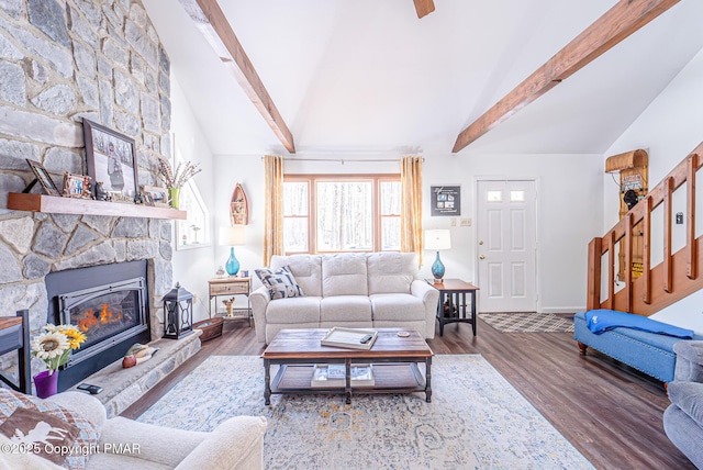 living room with wood finished floors, vaulted ceiling with beams, and a fireplace