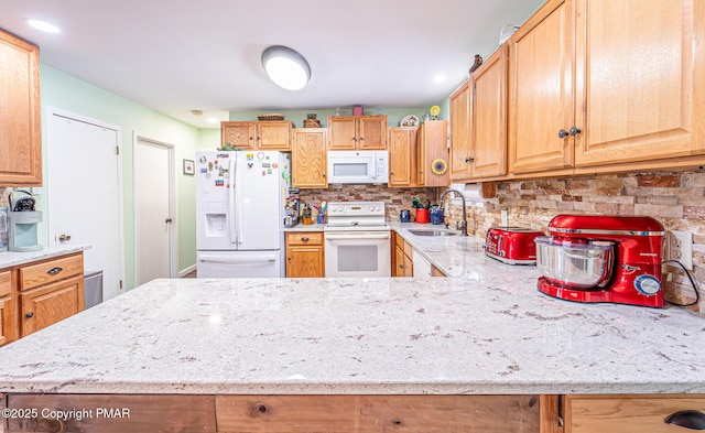 kitchen with light stone counters, decorative backsplash, white appliances, and a sink