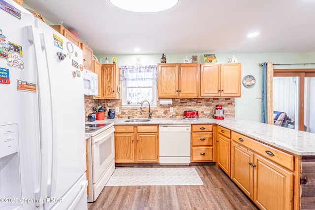 kitchen featuring backsplash, light wood-type flooring, a peninsula, white appliances, and a sink