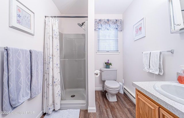 bathroom featuring vanity, wood finished floors, a baseboard radiator, a stall shower, and toilet