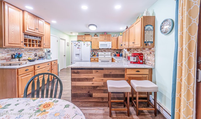 kitchen with white appliances, wood finished floors, a peninsula, and a sink