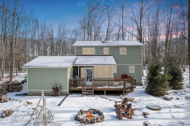 snow covered back of property featuring a deck and an outdoor fire pit