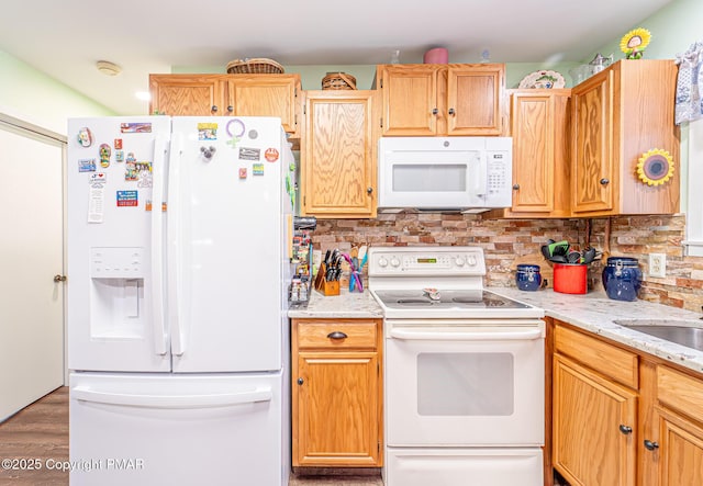 kitchen featuring a sink, white appliances, backsplash, and light stone countertops