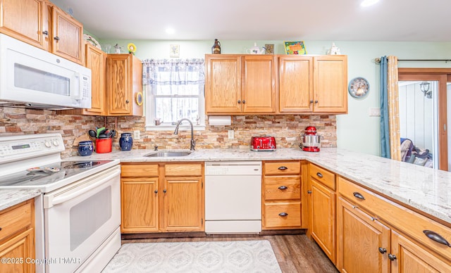 kitchen with a sink, tasteful backsplash, white appliances, light wood-style floors, and light stone countertops