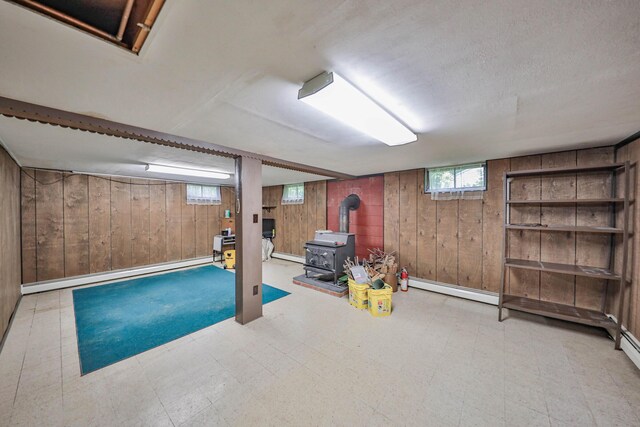 60 Maple Dr, Palmerton, PA 18071 - basement featuring wooden walls, baseboard heating, a wood stove, tile patterned floors, and plenty of natural light