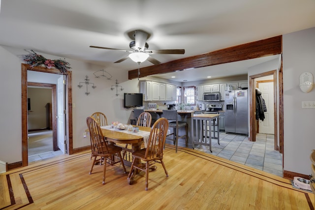 dining space with baseboards, ceiling fan, beamed ceiling, and light wood finished floors