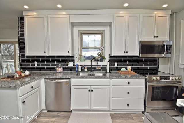 kitchen featuring stainless steel appliances, a sink, white cabinetry, and wood tiled floor