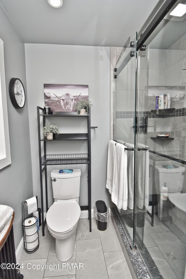 bathroom featuring toilet, a shower stall, and baseboards