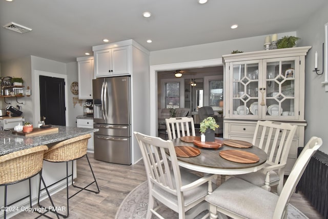 kitchen featuring stainless steel refrigerator with ice dispenser, recessed lighting, visible vents, light wood-style flooring, and glass insert cabinets