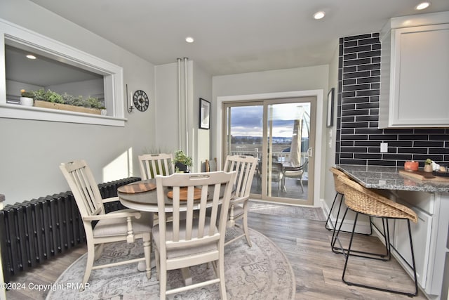 dining space with radiator, light wood-type flooring, and recessed lighting