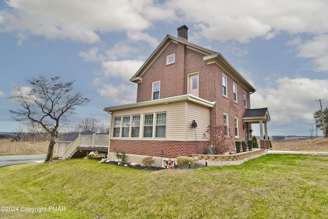 view of home's exterior featuring brick siding, a yard, and a chimney