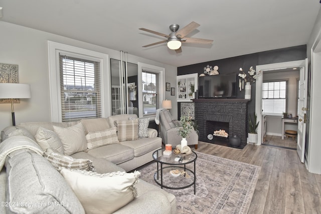 living room with ceiling fan, a fireplace, wood finished floors, and baseboards