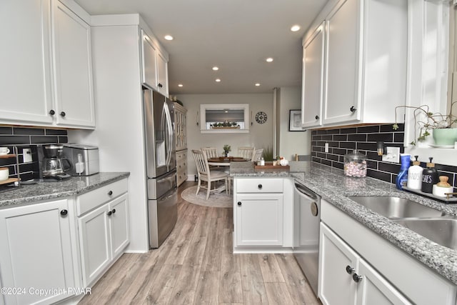 kitchen with recessed lighting, stainless steel appliances, a peninsula, white cabinets, and light wood-style floors