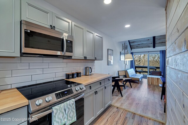 kitchen with butcher block countertops, light hardwood / wood-style flooring, appliances with stainless steel finishes, gray cabinetry, and hanging light fixtures