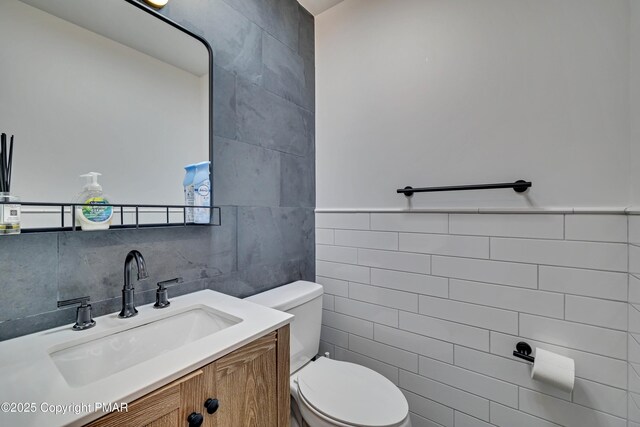 bathroom featuring tile walls, vanity, and toilet