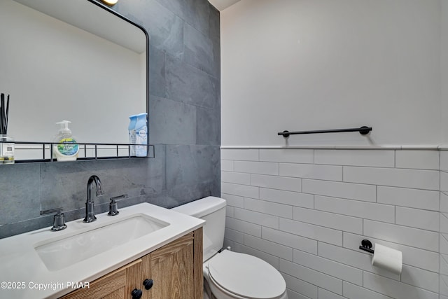 half bath with toilet, tile walls, and vanity