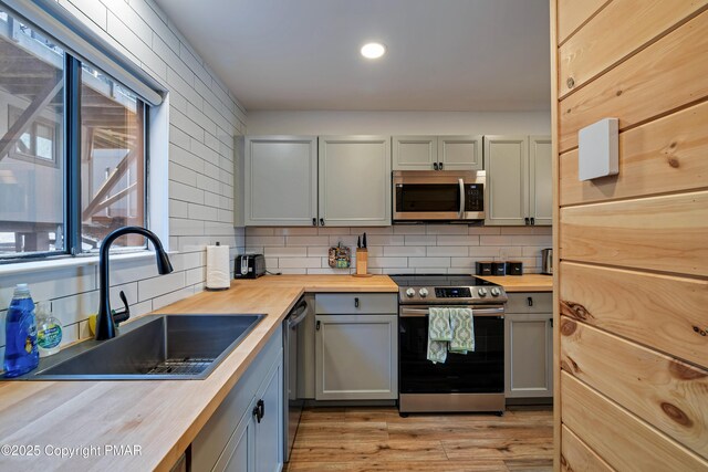 kitchen featuring stainless steel appliances, sink, wooden counters, and decorative backsplash