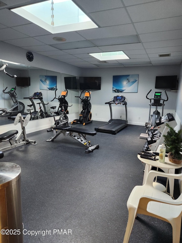 exercise room featuring a drop ceiling, visible vents, and baseboards