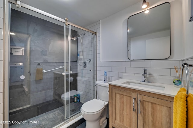 bathroom featuring a stall shower, tasteful backsplash, toilet, vanity, and tile walls