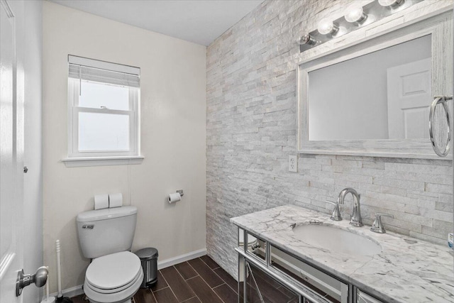 bathroom with vanity, baseboards, toilet, wood tiled floor, and decorative backsplash