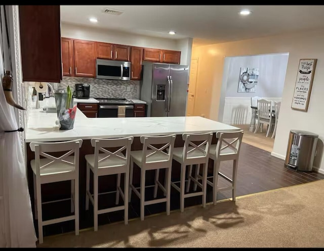 kitchen with a peninsula, visible vents, light countertops, stainless steel appliances, and a breakfast bar area