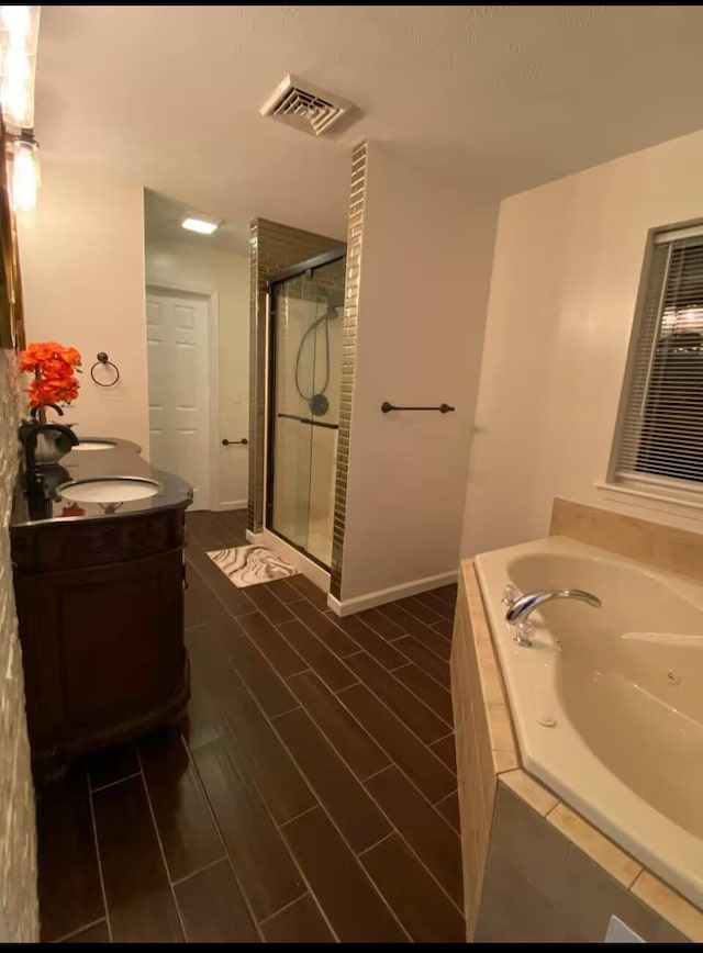 full bathroom with visible vents, a shower stall, vanity, wood finished floors, and a garden tub