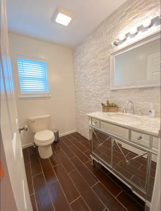 bathroom featuring toilet, wood finished floors, vanity, and baseboards