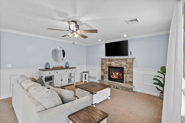 living room with visible vents, ceiling fan, a fireplace, carpet floors, and wainscoting
