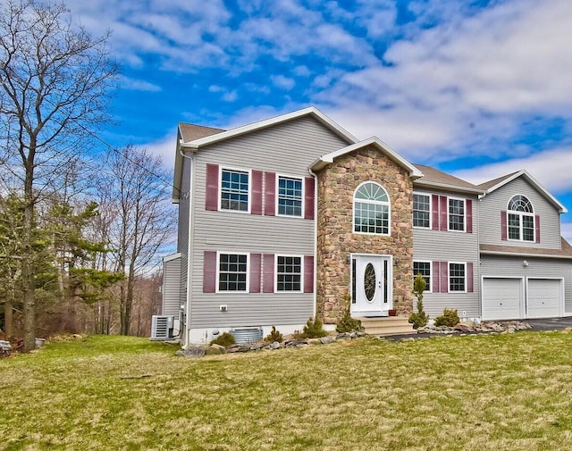 colonial house with cooling unit, stone siding, a front yard, aphalt driveway, and a garage