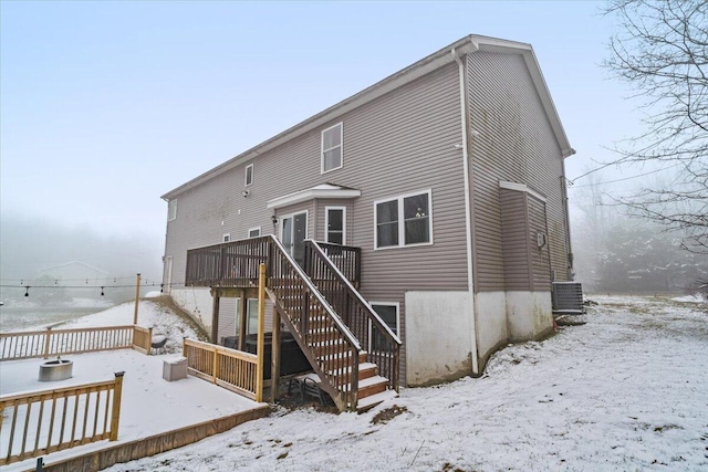 snow covered rear of property with central AC, a wooden deck, and stairs