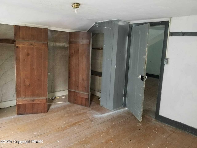 interior space featuring vaulted ceiling, wood-type flooring, and wooden walls