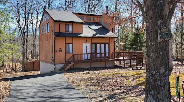 3221 Windermere Dr, Bushkill, PA 18324 - chalet / cabin featuring a shingled roof, a wooden deck, stairway, and a storage unit