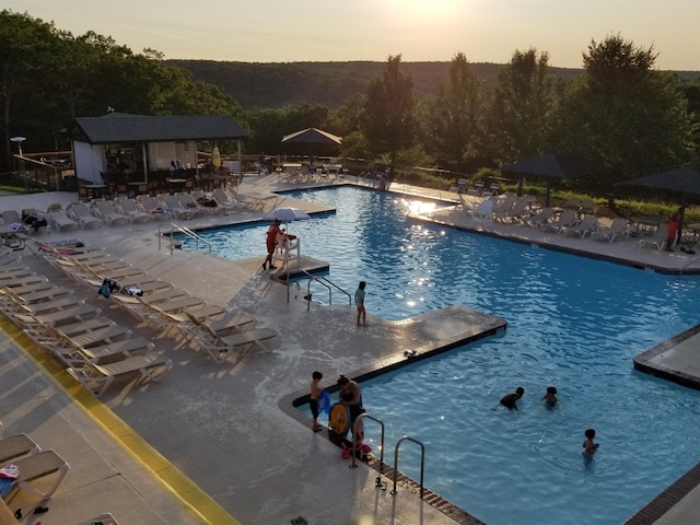 3221 Windermere Dr, Bushkill, PA 18324 - pool at dusk featuring a community pool, a patio, and an outbuilding