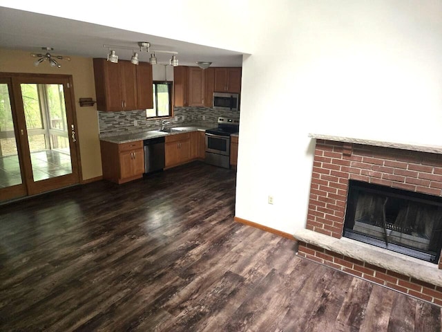 3221 Windermere Dr, Bushkill, PA 18324 - kitchen with stainless steel appliances, a brick fireplace, dark wood-style flooring, tasteful backsplash, and light countertops