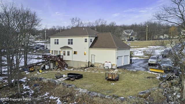 snow covered house with stairs, a lawn, a garage, and a shingled roof