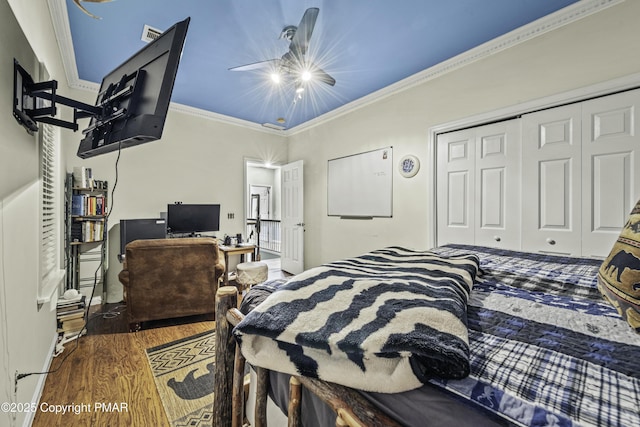 bedroom with dark wood-type flooring, ceiling fan, crown molding, and a closet