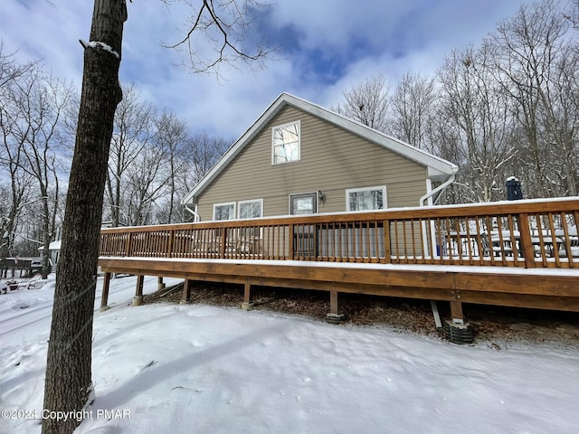 snow covered back of property featuring a wooden deck