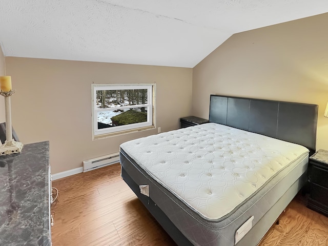 bedroom with light wood-style flooring, a textured ceiling, a baseboard radiator, baseboards, and vaulted ceiling