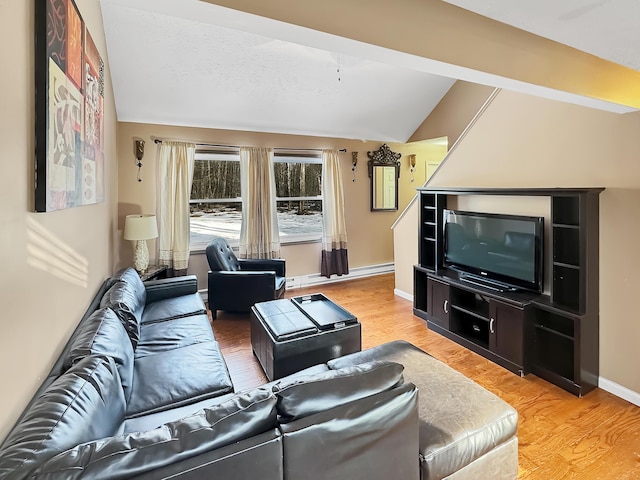 living area featuring light wood finished floors, baseboards, and vaulted ceiling