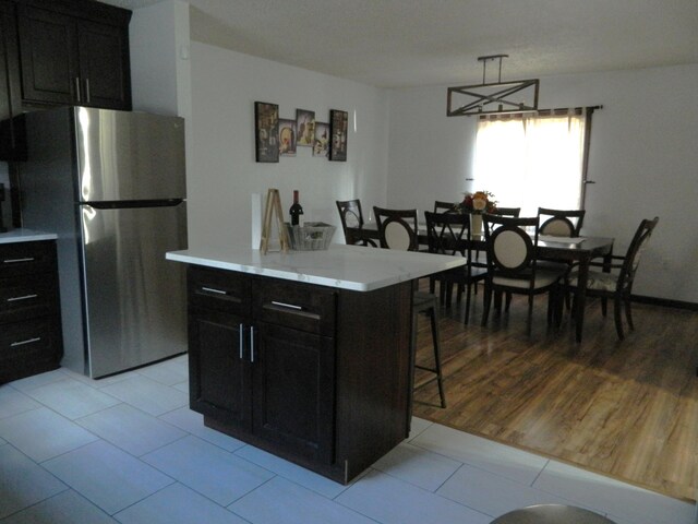 7086 Boulder Ct, Tobyhanna, PA 18466 - kitchen with freestanding refrigerator, a kitchen breakfast bar, light countertops, dark cabinets, and light tile patterned flooring