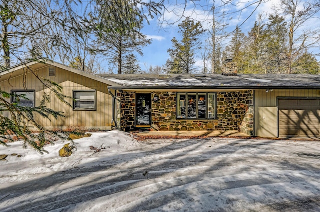 view of front of property featuring stone siding, a chimney, and an attached garage