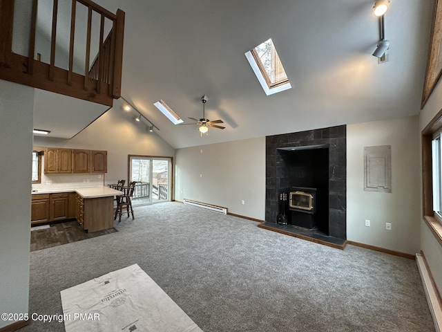 unfurnished living room featuring rail lighting, a baseboard heating unit, dark carpet, and a skylight