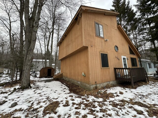 view of snowy exterior featuring a shed