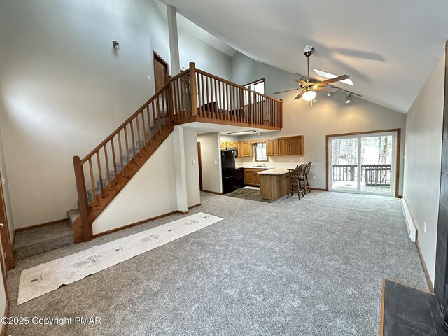 unfurnished living room featuring high vaulted ceiling, light colored carpet, and ceiling fan